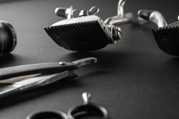 On a black surface are old barber tools. Two vintage manual hair clipper, razor, shaving brush, hairdressing scissors. black monochrome. horizontal
