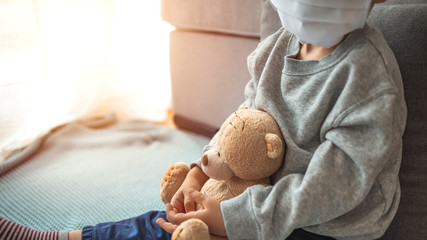 Stay at home quarantine coronavirus pandemic prevention. Sad child and his teddy bear both in...