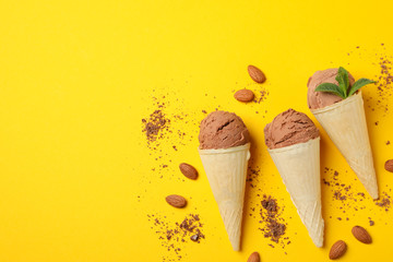 Ice cream in cones and almond on yellow background. Sweet food