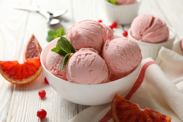 Bowls with ice cream balls on white wooden table, close up