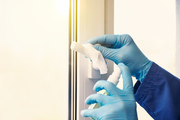 doctor in rubber gloves disinfects window handles with sanitizer and napkins