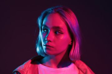 Young woman in pink and violet neon light. Portrait of unusual beautiful glamour and fashion girl with colorful hairstyle on studio background.