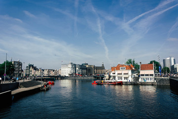 Fototapeta na wymiar Summer cityscape of Amsterdam. Modern architecture. Touristic boats in canal. Tourism in Europe.