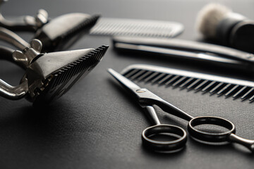 black surface are old hairdresser tools. Two vintage hand-held hair clippers, combs, razor, hairdressing scissors, shaving brush. black monochrome.