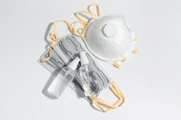 Top view of sanitizer antiseptic gel bottles and respiratory medical flu masks against coronavirus, on white table.
