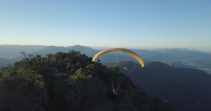 Fly following a paraglider near the green mountains of Santa Catarina