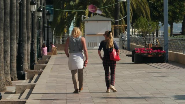 Man and woman walk down the street under the Sun  slowmotion in Marbella, Spain