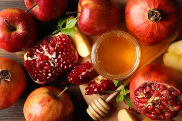 Apples, pomegranate and honey on wooden background, top view