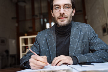 Image of handsome unshaven young businessman examining documents