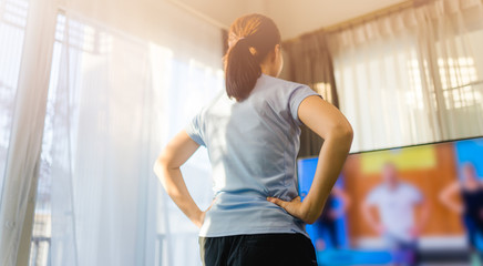 Video streaming Stay home.home fitness workout class live streaming online.Asian woman doing strength training cardio aerobic dance exercises watching videos on a smart tv in the living room at home.