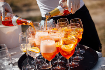 barman pours sparkling wine into a glass in aperol spritz cocktail 