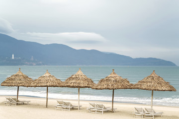 Palm shelters with sunbeds in China Beach in Da Nang
