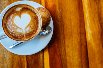 Close up cup of cappuccino in a white cup on a saucer with cookies. Top view copy place