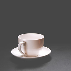 A white ceramic coffee cup stands on a black background