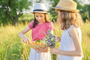 Children two girls on sunny summer day in meadow with bowl of sweet cherry