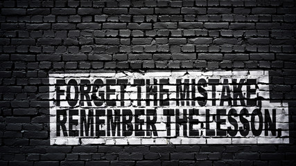 Fototapeta na wymiar forget the mistake, remember the lesson, motivation and inspiration slogan, white text on black brick wall