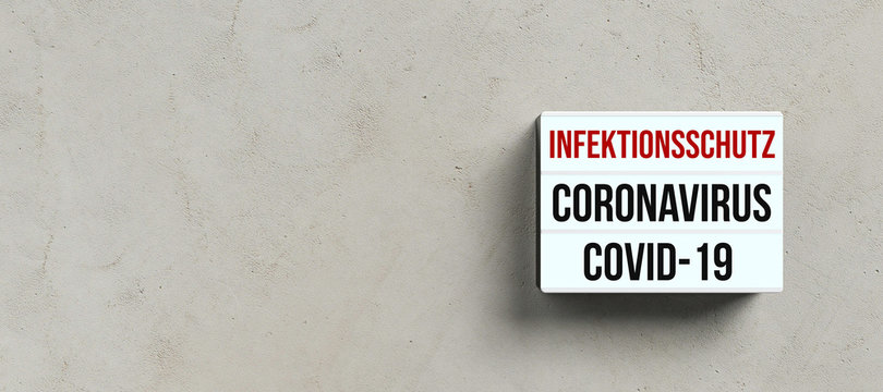 lightbox with text CORONAVIRUS COVID-19 and INFECTION PROTECTION in German on a concrete wall