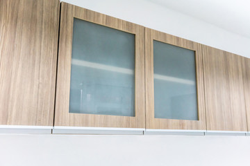 Modern style wood cabinet with glass doors hanging on wall.
