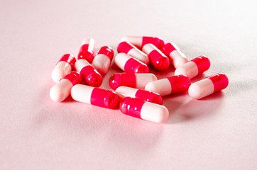 White oval heart-shaped tablets lie on a pink background.