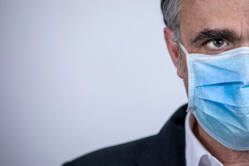 Ritratto di uomo di mezza età che indossa una mascherina chirurgica azzurra isolato su sfondo...