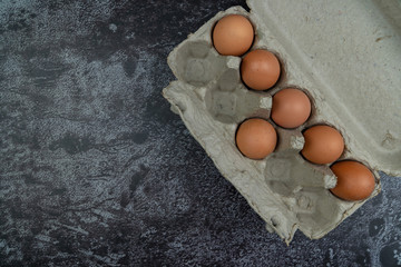 Brown color eggs on dark background. Top view with copy space.