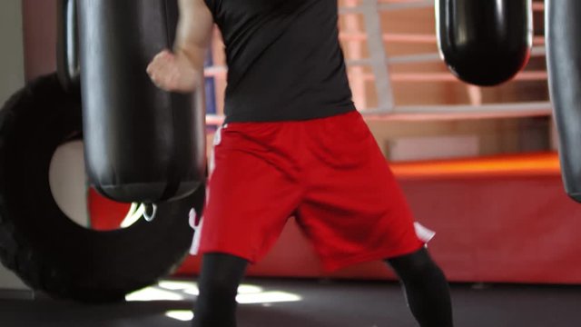 Strong male boxer in sportswear working out with double agility in gym: he doing footwork exercise and punching the air