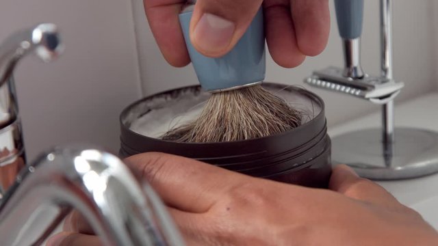 b-roll closeup of male hand hold a shaving foam bottle and dip and lift up a shaving brush