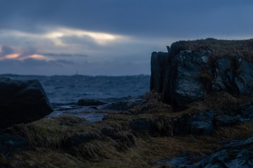 Rocks and grass in foreground, ocean and clouds as background