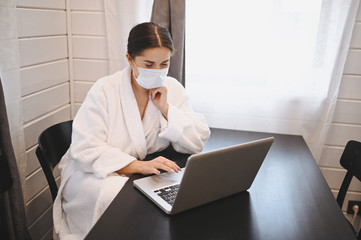 Sick woman in face medical mask working on a laptop during home quarantine isolation COVID-19 pandemic Corona virus. Distance online work from home concept. Coronavirus viral infection  symptoms