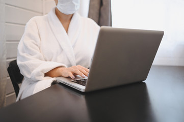 Sick woman in face medical mask working on a laptop during home quarantine isolation COVID-19 pandemic Corona virus. Distance online work from home concept. Coronavirus viral infection  symptoms