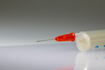 Injection needle of a syringe before grey background