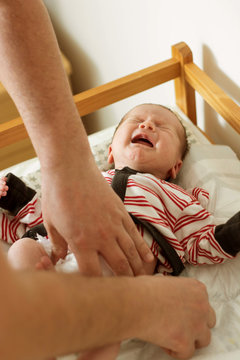 Parent changing baby's diaper indoors,