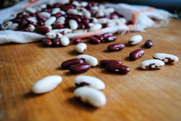 Ripe red and white beans sprinkled on a wooden table