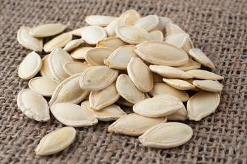 Fresh pumpkin seeds on burlap. Autumn vegetables.