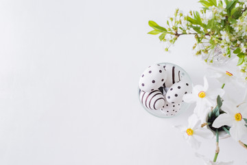 Flat lay easter composition with spring flowers in a vase and easter eggs on a light background