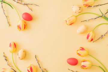 Flat lay easter composition with yellow tulips and eggs on a yellow background