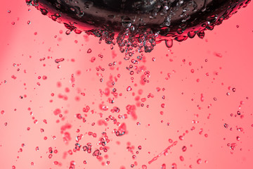 many trickles and drops of water through holes in a meialic colander on a red background