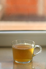 Cup of herbal tea on a window sill. Selective focus.