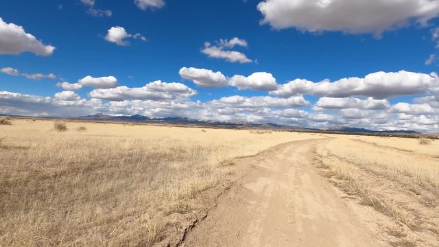 Driving dry arid desert trail driving fast POV . Off road trail riding in 4x4 all terrain vehicle for sport and recreation. Dry arid landscape. Grass lands, rocky terrain and sand dunes.