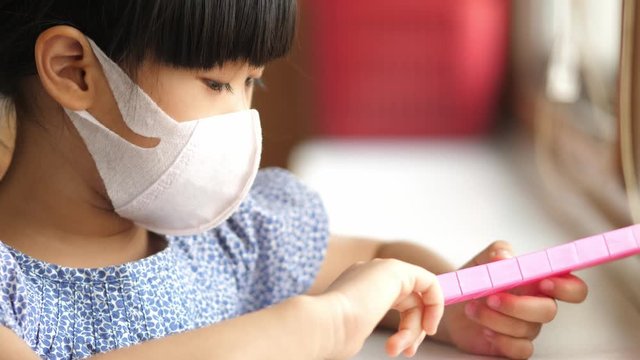 asian girl wear mask protech pm2.5 covid corona virus and playing toy at home.