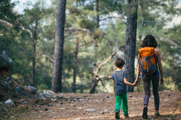 A woman walks with her son through the forest.