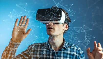 Man wearing virtual reality glasses watching at a 3D visualization in an abstract polygonal grid in...