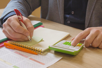 Different objects on wooden desk. Modern wooden office desk table with and hand holding documents, money and signing