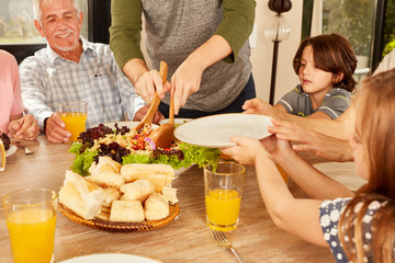 Vater verteilt Salat mit dem Salatbesteck