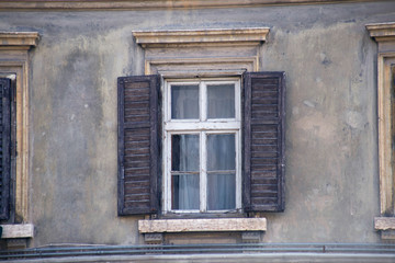 Fototapeta na wymiar Italian window on the old wall facade with open wooden shabby brown paint shutters