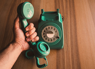 Teléfono vintage de color verde sobre mesa de madera