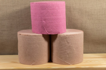 Three rolls of toilet paper lie on a wooden board.