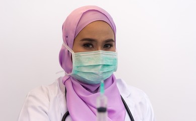 Shallow DOF and selective focus on the muslim woman doctor while she holding her syringe.