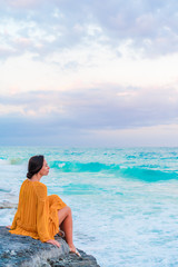 Young beautiful woman on tropical seashore in sunset.