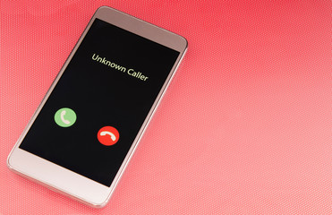 Unknown caller. White smartphone with incoming call from an unknown number on a red background....
